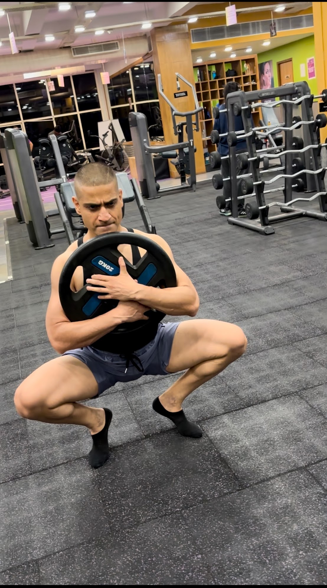 Shiva Malhotra ACE certified personal trainer performing a deep goblet squat with a 20kg weight plate, demonstrating leg strength training for adults over 35