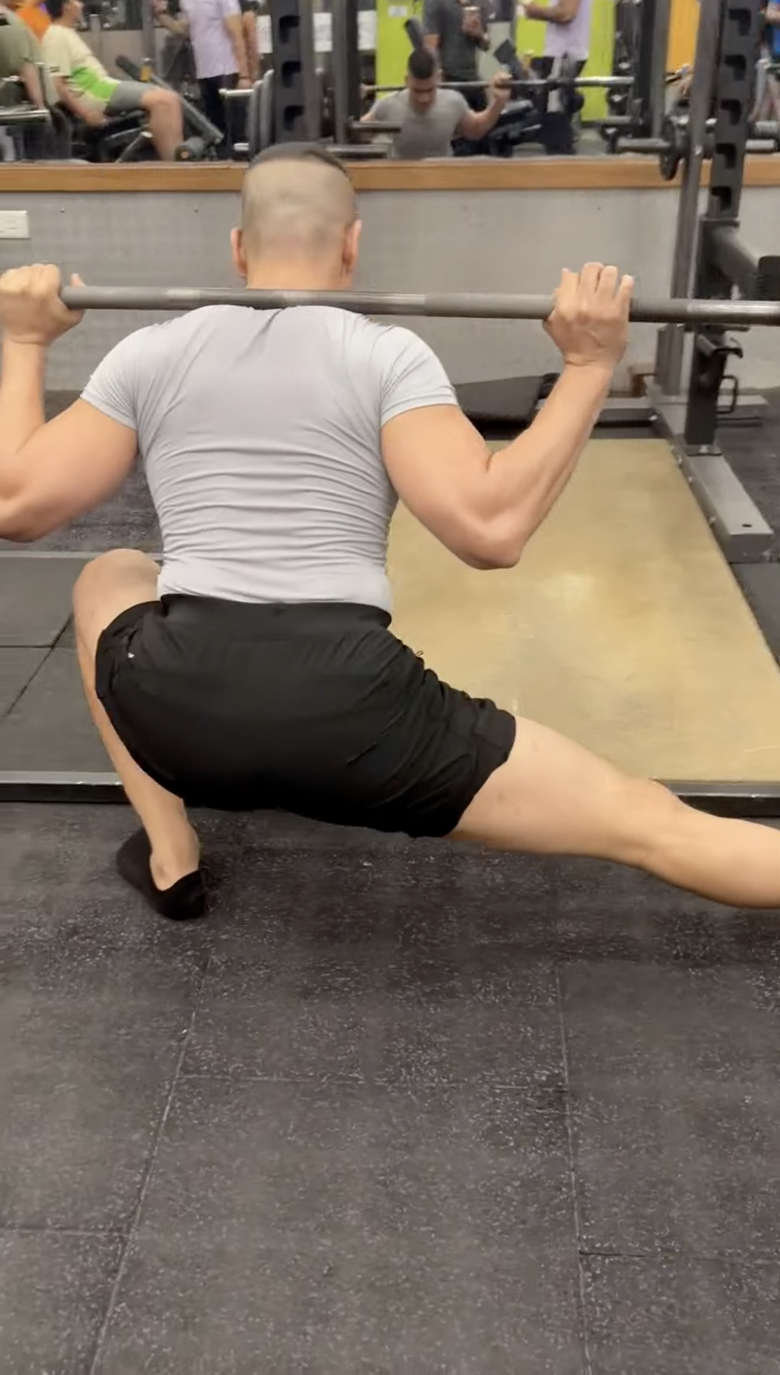 Shiva Malhotra ACE certified personal trainer performing a deep lateral Cossack squat with a loaded barbell, demonstrating demanding strength training for adults over 35