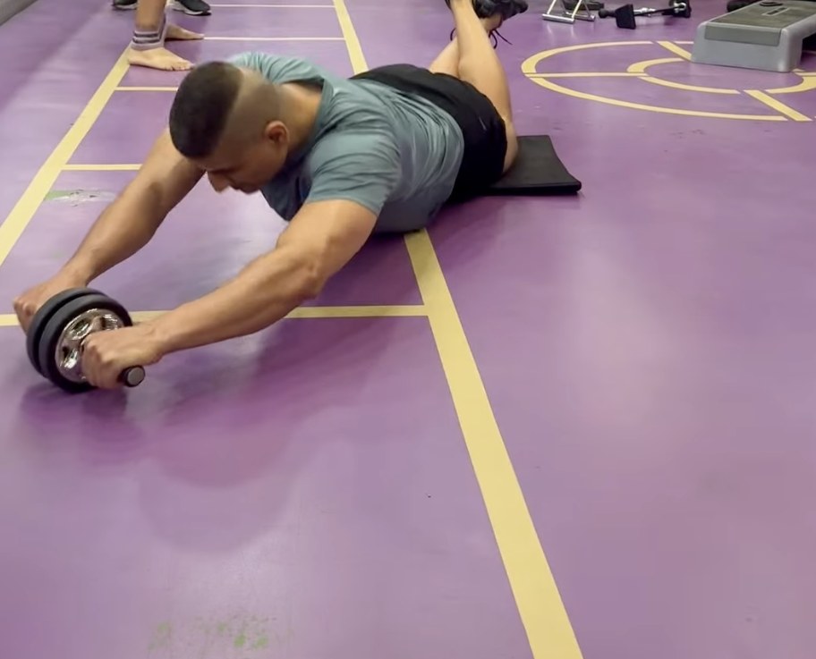 Shiva Malhotra performing a diagonal ab wheel rollout — rotating 30 to 45 degrees to target the obliques and side abs, adding a new dimension to core training for adults over 35